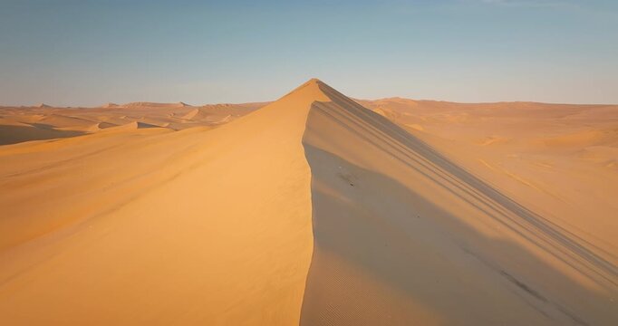 Drone flight over crest of sand dune in desert near Huacachina in South America