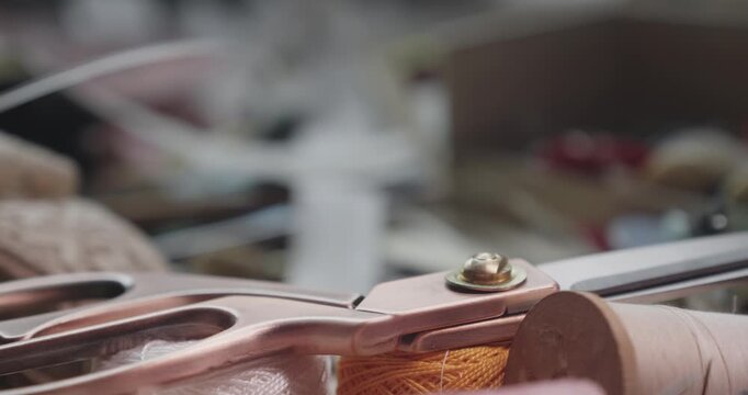 Close-up of tailoring scissors resting on cotton thread cones, highlighting garment production tools and traditional textile craftsmanship.