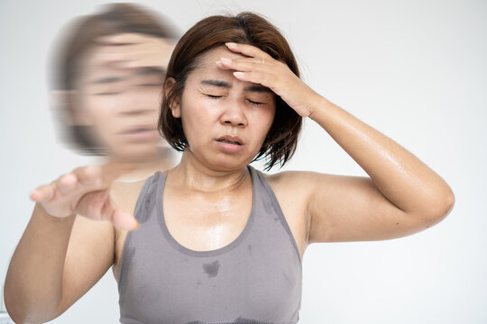 Exhausted Asian woman feeling dizzy, lightheaded, and faint after workout, suffering from heat stroke, dehydration, fatigue, and headache during fitness training