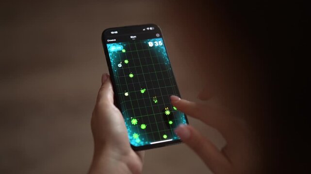 Woman hands holding modern smartphone and playing dynamic arcade video game, tapping touchscreen to score points in dimly lit room, focusing on entertainment and digital technology, slow motion.