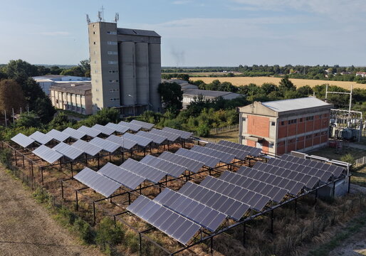 Aerial view of solar panel array in the South Industrial Zone with a tall concrete silo and industrial buildings in the background in Pancevo, Serbia.