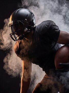 Intense football player gripping ball in dramatic smoke, action shot