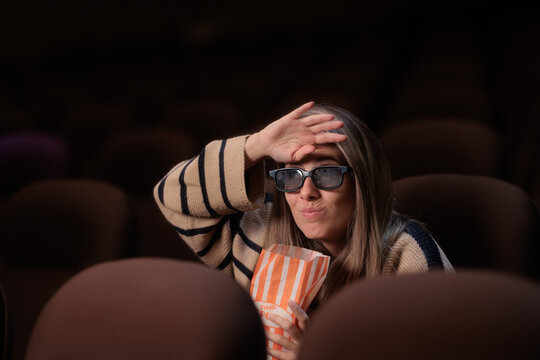 Uncomfortable Woman Wearing 3D Glasses Watching Intense Cinema Movie. Tense girl holding popcorn looks awkward shielding eyes in movie theater