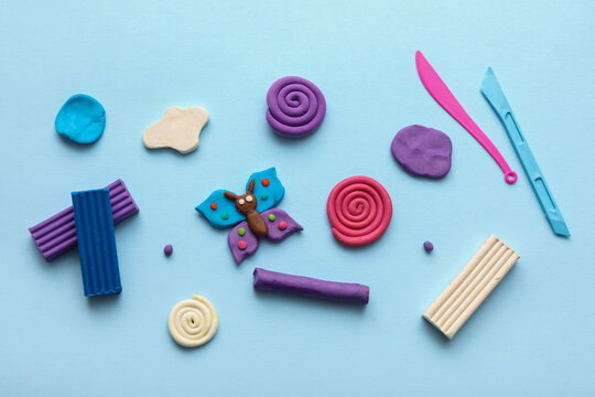 Many different colorful plasticine with figurines and plastic knives on blue background