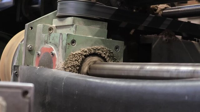 Heavy duty manufacturing machine component spinning with visible fiber buildup and pulp dust accumulation during corrugated board production.