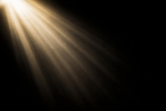 Golden light beam with dust particles isolated on black background, abstract light effect, spotlight, sun rays, lens flare, overlay