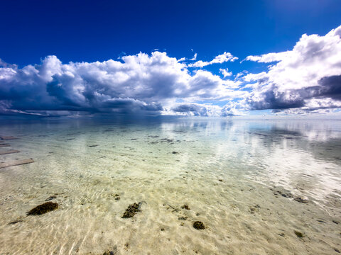 Shallow tropical lagoon beneath dramatic clouds with clear water and visible sandy seabed at Heron Island, Queensland, Australia.