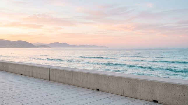 Wide sea expanse meeting gentle hills with a concrete barrier in the foreground.