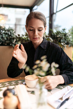 Morning coffee break featuring a young woman sitting at a cafe table while enjoying a peaceful moment of reflection