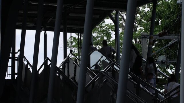 Silhouette Figure Walking Down Escalator Through Steel Beam Skytrain Structure
