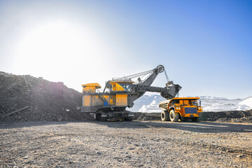 Coal mining in winter, excavator and dump truck big yellow car in open pit mine under clear sky © Parilov