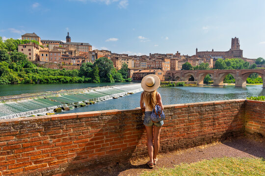 Woman tourist with straw hat looking at Albi cathedral river bridge and dam back view summer travel france