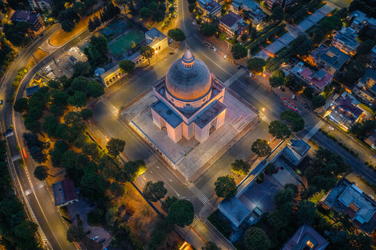 Aerial view of the Basilica dei Santi Pietro e Paolo in the EUR district, illuminated at night, surrounded by urban streets and trees in Rome, Lazio, Italy.