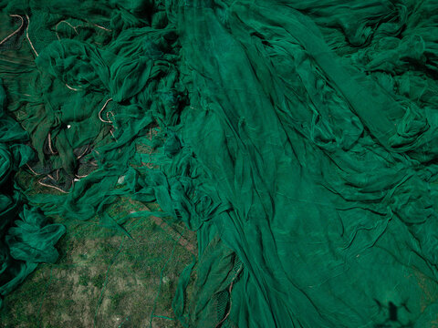 Close-up of green fishing nets spread out on grass in vietnam