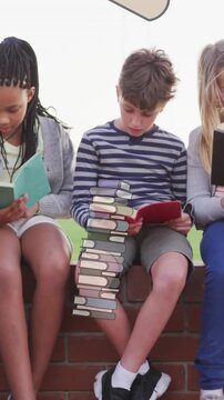 Animation of books moving over happy diverse school kids reading book at school