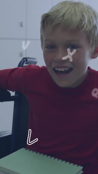 Animation of letters over happy caucasian schoolboy in wheelchair