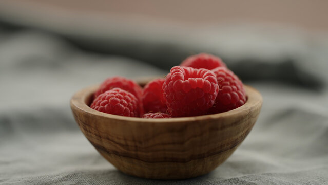 fresh ripe raspberries in a small wooden bowl