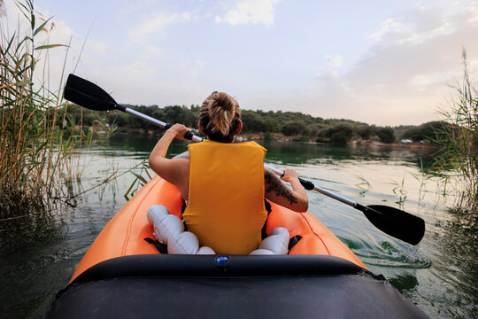 Woman kayaking on lake exploring nature at sunset