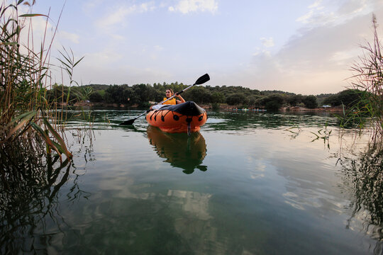 Woman paddling inflatable kayak discovering nature on calm lake