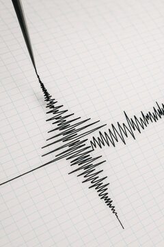 Seismograph recording earthquake waves on graph paper showing natural disaster data and geology research concept with black ink lines and grid background