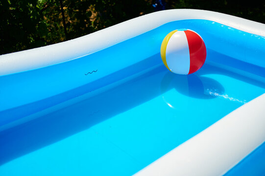 A colorful beach ball floating in an inflatable blue backyard swimming pool