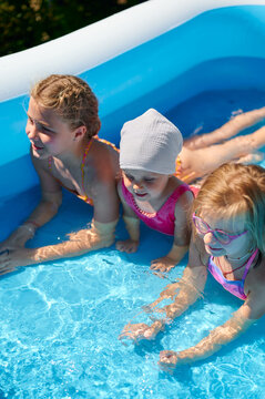 Happy children playing and swimming in an inflatable pool on a sunny summer day