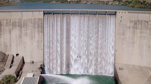 Water release from a dam at full capacity. Aerial view. Spillway and discharge valve releasing reservoir water at full capacity. Rules Dam. Spain.