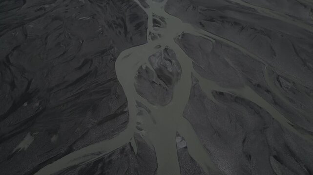aerial perspective revealing intricate braided river patterns flowing across the valley floor beneath the spectacular Passu Cones in northern Pakistan