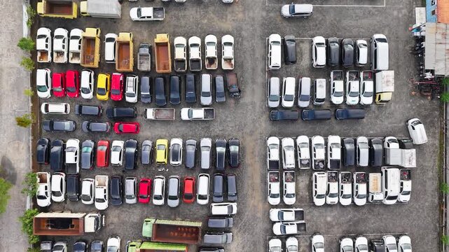 The parking lot was filled with cars lined up for rent, and there were several cars damaged in accidents parked there.