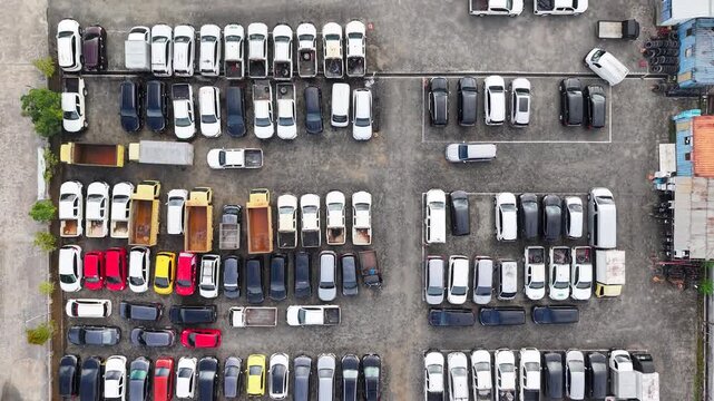 The parking lot was filled with cars lined up for rent, and there were several cars damaged in accidents parked there.