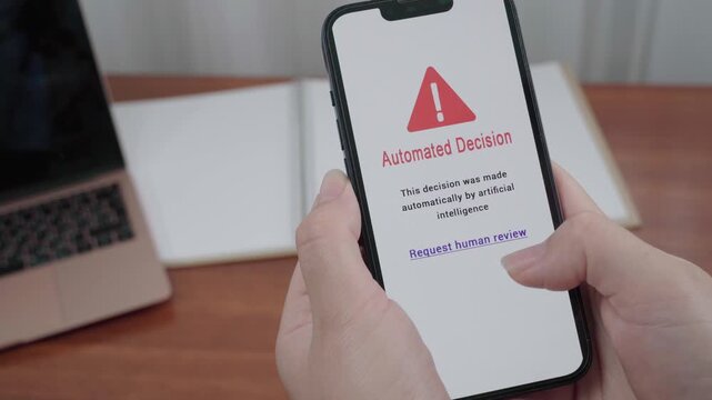 Hands hold a mobile device displaying an Automated Decision AI alert with a prominent Request human review link.