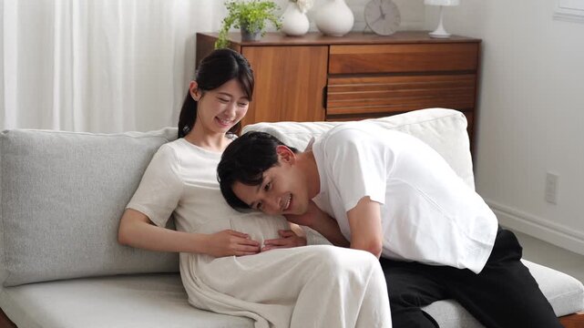 妊娠中の妻のお腹に耳を当てる夫