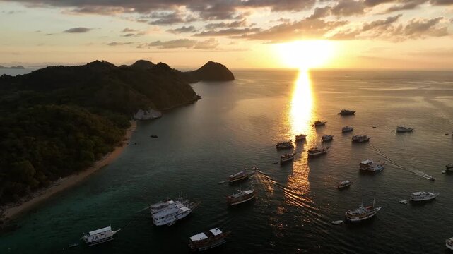 Aerial view of Labuan Bajo with numerous boats anchored in the bay during a golden sunset, Komodo, East Nusa Tenggara, Indonesia.