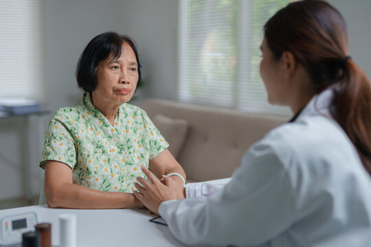 Doctor comforting senior Asian woman patient during consultation