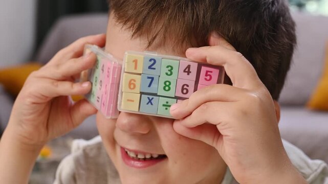 Close Up of Child Holding Educational Math Blocks Learning Numbers Arithmetic and Problem Solving During Fun Home Education Activity. Boy plays with numbers, closes eyes