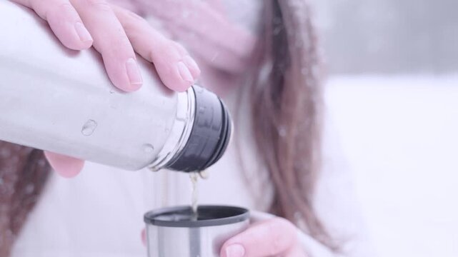 Woman outdoor break. Female serving tea during snowfall. Mindful pause concept.