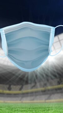 Animation of covid 19 signs and face mask over sports stadium