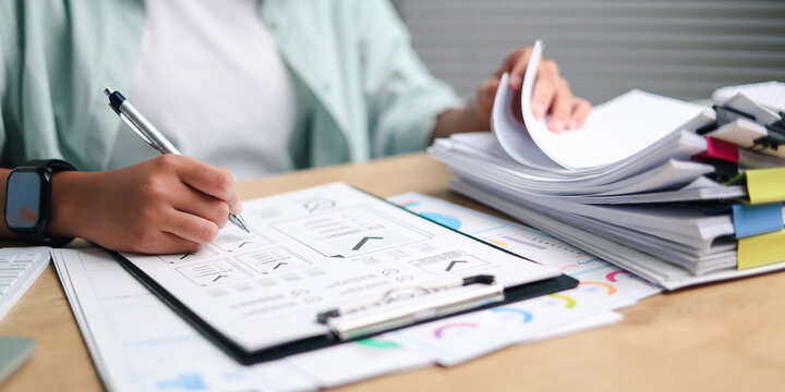 Professional reviewing business documents and reports at an office desk, illustrating paperwork, financial analysis, project planning, productivity, administration, research.