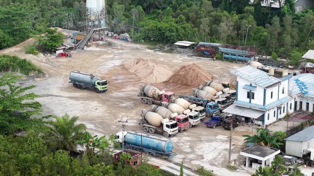 Aerial view of cement mixer trucks parked in a row and piles of raw materials for cement production