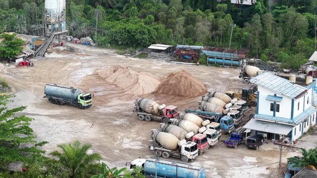 Aerial view of cement mixer trucks parked in a row and piles of raw materials for cement production