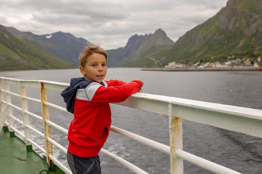 European family, kid with pet dog, enjoying ferry ride between Senja and Andenes Andoya summertime, child and adults on a ferry on sunset