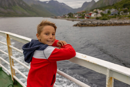 European family, kid with pet dog, enjoying ferry ride between Senja and Andenes Andoya summertime, child and adults on a ferry on sunset