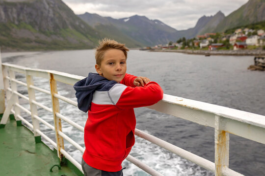 European family, kid with pet dog, enjoying ferry ride between Senja and Andenes Andoya summertime, child and adults on a ferry on sunset