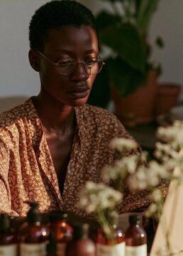 Portrait of a young african-american woman sitting at a table with several bottles of essential oils in front of her.