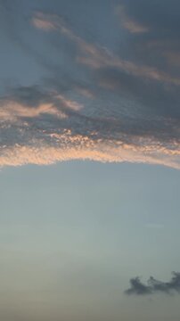 Vertical video of soft textured clouds glowing in warm sunset light against twilight sky