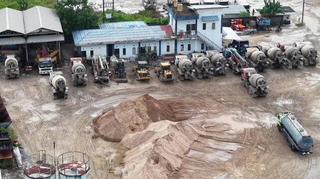 Aerial view of cement mixer trucks parked in a row and piles of raw materials for cement production