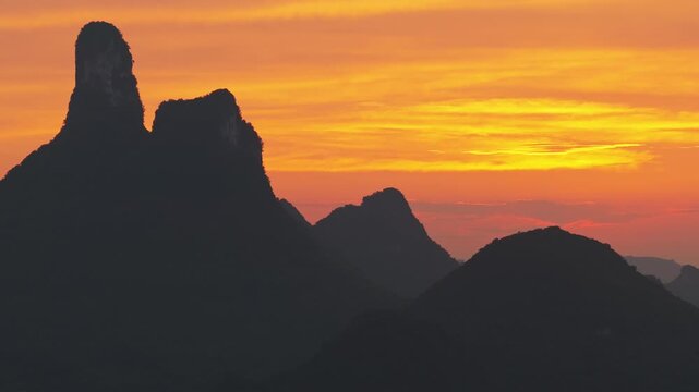 Aerial view of the karst mountains in Yangshuo County at sunset with a vibrant orange sky over the landscape in Guilin, Guangxi, China.