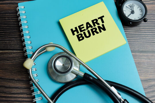 Concept of heart burn write on sticky notes with stethoscope isolated on Wooden Table.