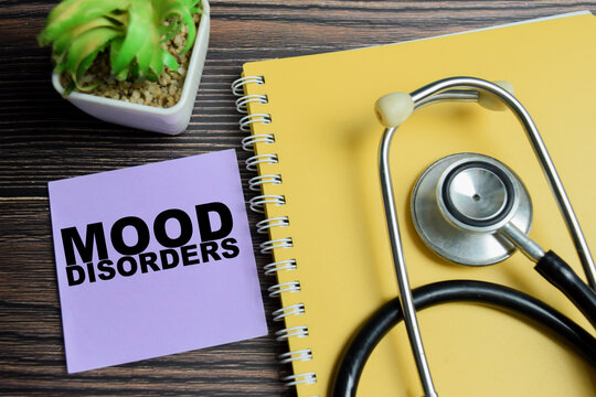 Concept of mood disorders write on sticky notes with stethoscope isolated on Wooden Table.