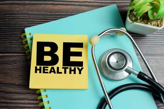Concept of be healthy write on sticky notes with stethoscope isolated on Wooden Table.